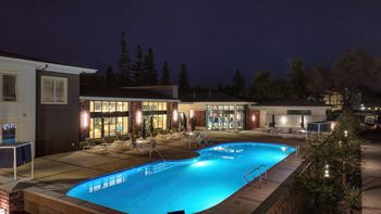 a large swimming pool in front of a building at night